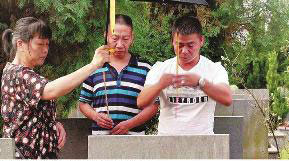 Ma Jianhua (right) and Li Rongfu (middle) pay respect to their deceased parents after going home 44 years later. [Photo/Huashang Daily]