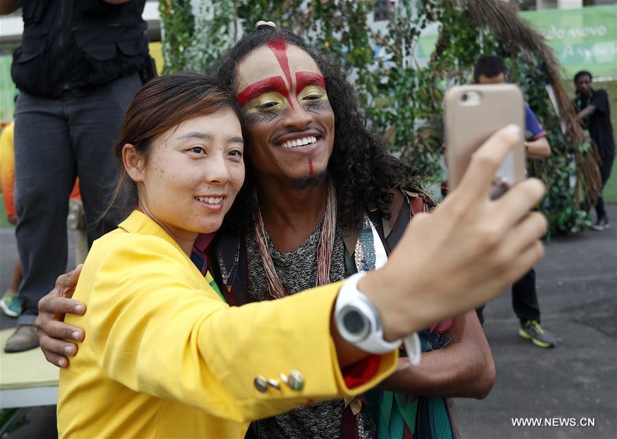 Chinese tennis player Xu Yifan takes a selfie with a performer after the flag-raising ceremony at the Olympic Village in Rio de Janeiro, Brazil, on Aug. 3, 2016. (Xinhua/Shen Bohan) 