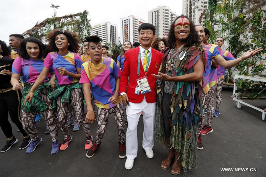 A member of the Chinese delegation poses for photos with performers after the flag-raising ceremony at the Olympic Village in Rio de Janeiro, Brazil, on Aug. 3, 2016. (Xinhua/Shen Bohan) 