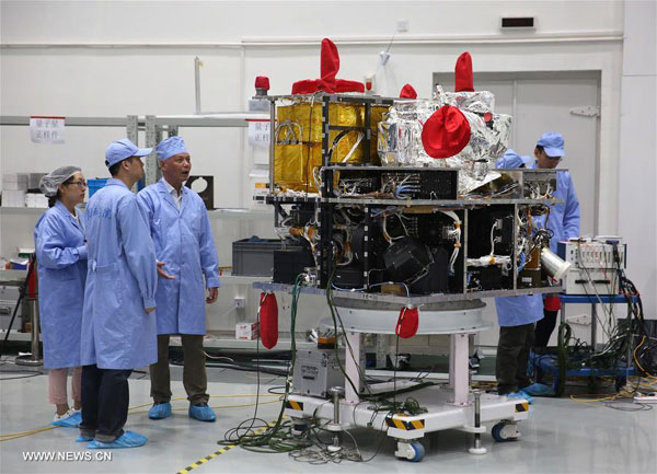 Deputy Chief Engineer Zhou Yilin (L3) discusses with other technicians beside the quantum satellite at Shanghai Engineering Center for Microsatellites, under the Chinese Academy of Sciences, in Shanghai, May 25, 2016. [Photo: Xinhua]  