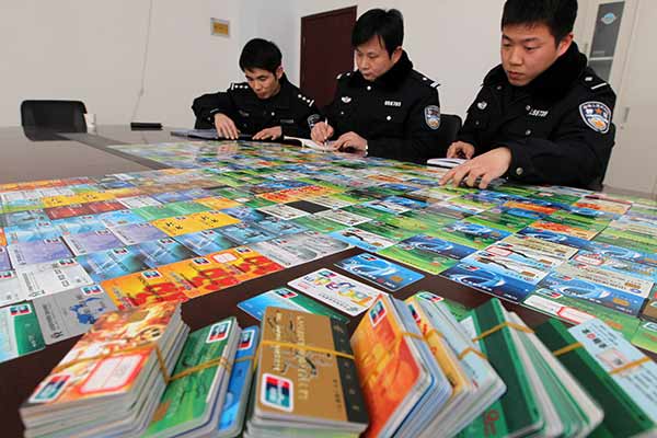 Police officers make a list of bank cards seized in a telecommunication fraud case in Xuchang, Henan province, in January. [Photo/China Daily]