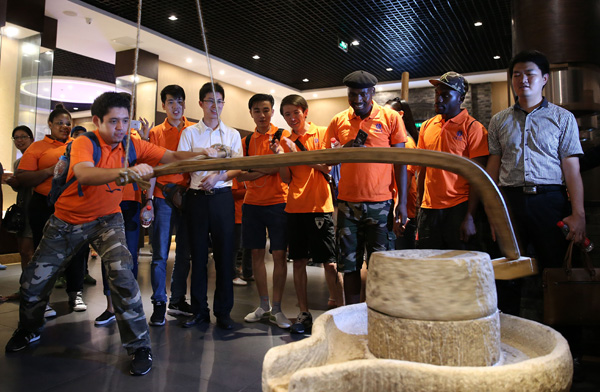 International students from Southwest University in Chongqing learn how to use a traditional Chinese mill to produce flour at a museum in the city. [Photo / China Daily]