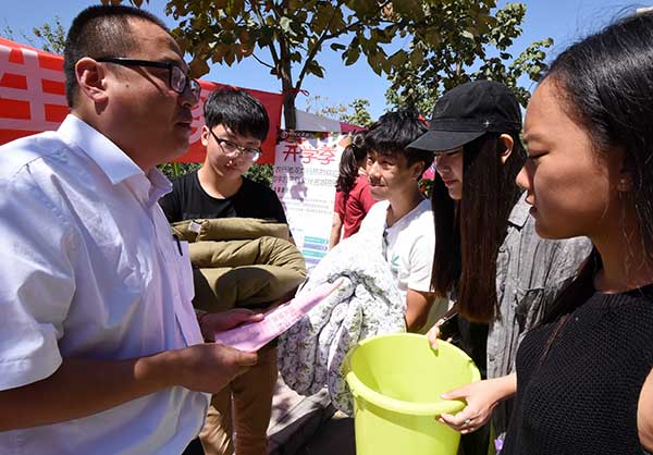 A worker from the Handan Branch of Agricultural Bank of China tells new students how to distinguish telecom fraud at Hebei University of Engineering on their first day at the school.[Hao Qunying/for China Daily]