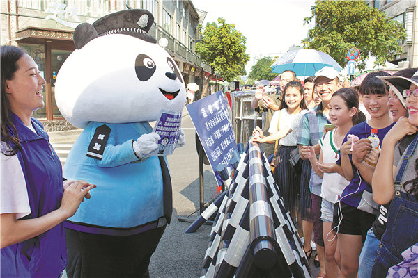 Shen Yijie,a junior at Zhejiang Police College, wears a cartoon panda costume while providing assistance to tourists lined up at the security check for admission to Hangzhou's West Lake. The city has beefed up security ahead of the G20 summit. [Photo/China Daily]