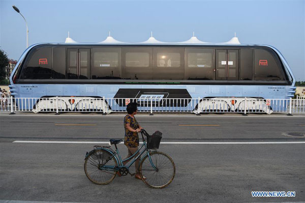 A citizen walks past a Transit Elevated Bus (TEB) which is on road test in Qinhuangdao, north China's Hebei Province, Aug. 2, 2016. China's home-made transit elevated bus, TEB-1, conducted a road test running Tuesday. [Photo: Xinhua]