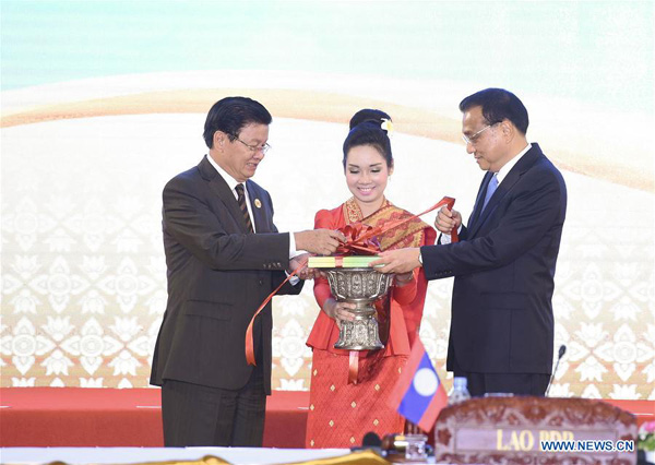 Chinese Premier Li Keqiang (1st R) and Laotian Prime Minister Thongloun Sisoulith (1st L) cut the ribbon for the handbook titled &apos;25 Years of ASEAN-China Dialogue and Cooperation: Facts and Figures&apos; as they attend a ceremony to commemorate the 25th anniversary of the establishment of China-ASEAN dialogue relations, in Vientiane, Laos, Sept. 7, 2016. (Xinhua/Gao Jie) 