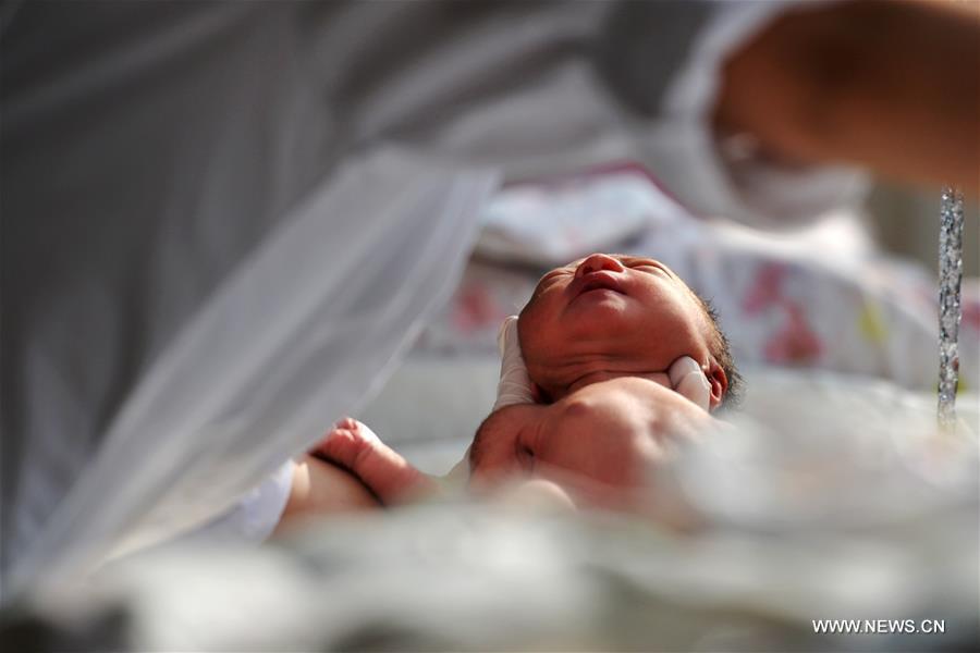 A newborn is held by a nurse before taking a bath at the Gansu Provincial Maternity and Child-care Hospital in Lanzhou, capital of northwest China's Gansu Province, Feb. 17, 2016. The hospital saw a baby boom at the beginning of the Chinese Lunar New Year, with 352 babies born from Feb. 8 to 15.[Photo/Xinhua]