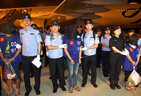 Police officers escort telefraud suspects at Nanjing Lukou International Airport in Jiangsu province last Tuesday. A total of 63 suspects were brought back from Cambodia and accused of defrauding people on the Chinese mainland by posing as law enforcement officials. Han Yuqing / Xinhua
