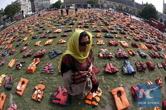 Rehab Sidiqi, a trustee of Woman for Refugee Woman and originally from Afghanistan, poses for a photograph among 2500 lifejackets worn by refugees during their crossing from Turkey to the Greek island of Chois, in Parliament Square in central London, Britain September 19, 2016. [Photo/Xinhua]
