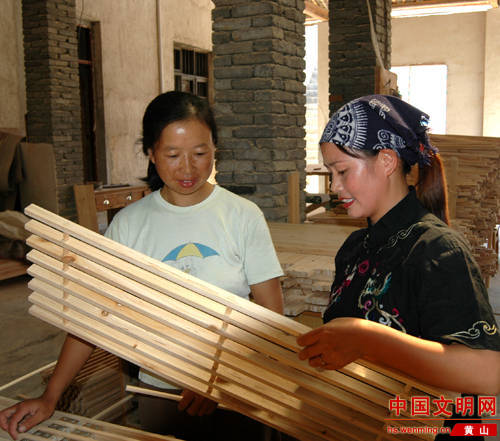 Jin Yuqin (R) in her woodcraft factory