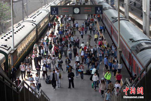 A file photo shows passengers walk to board the trains. [File photo: Chinanews.com]