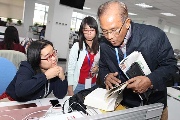  Win Tin (right), from Myanmar, and Pham Thi Hai Ha (middle), from Vietnam, visit China Daily newsroom during their training program in Beijing on Sept 28. [Photo/China Daily]