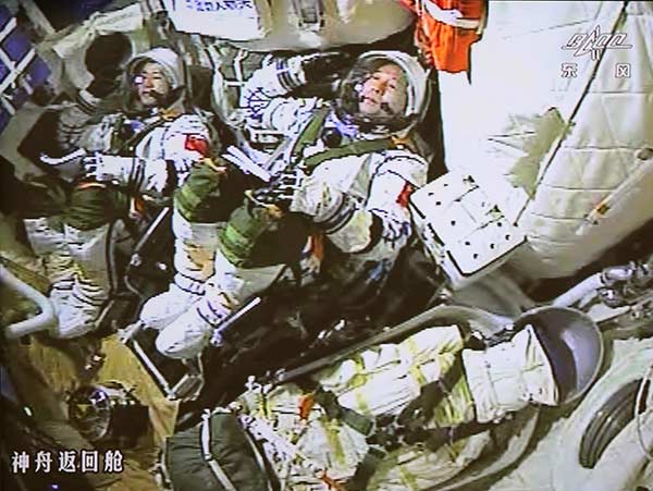 Astronauts Jing Haipeng (right) and Chen Dong salute inside the spacecraft at the moment of launching on Monday. [Photo/Xinhua] 