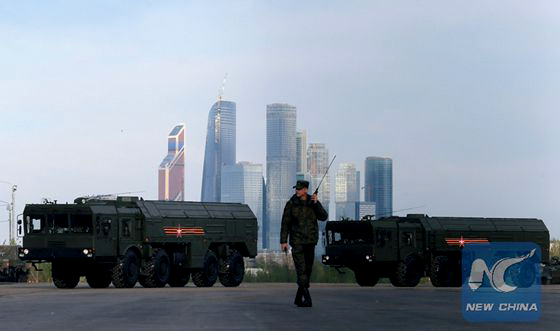 A Russian serviceman walks past Russian Iskander-M missile launchers before a rehearsal for the Victory Day parade, with the Moscow International Business Center also known as 'Moskva-City' seen in the background, at a range in Moscow, Russia, May 5, 2016. [Photo/Xinhua]