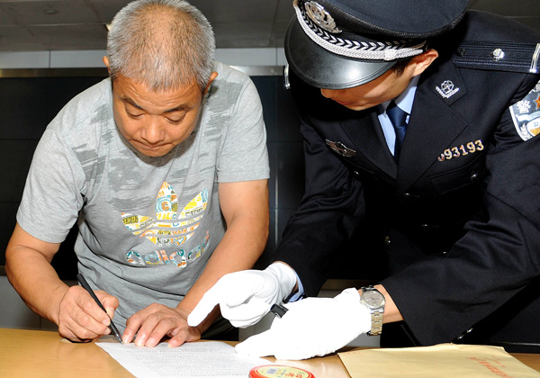 Zhao Ruheng, one of China's 100 most-wanted fugitives, countersigns his arrest warrant at Shanghai Pudong International Airport after being repatriated in November last year. [Photo/Xinhua]