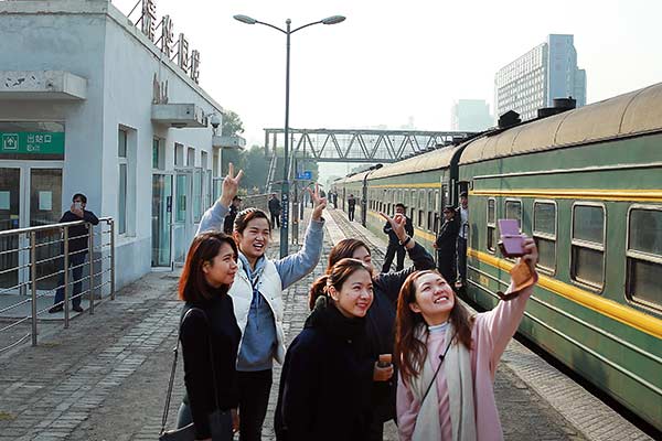 Students from Macao, who are studying in Beijing, take photos at Qinghuayuan Railway Station as their train makes a stop at the station on Tuesday. [China Daily]