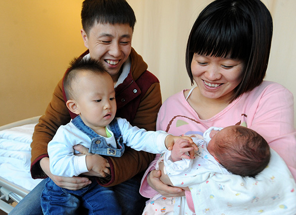 A couple both born after 1990 hold their children, an infant daughter and her 18-month-old elder brother, in Shenyang, Liaoning province, on Jan 3.Many couples responded to the chance to have a second child after policies were eased. [Photo/China Daily]