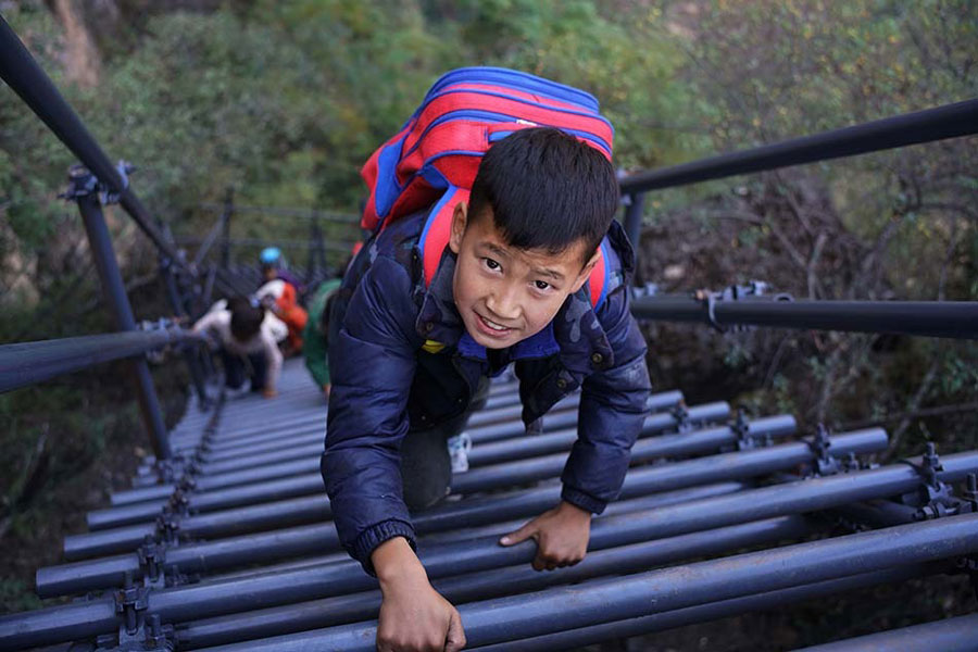 Children climb a steel ladder leading to the cliff village in Sichuan province on Saturday, November 19, 2016. [Photo: The Beijing News] 