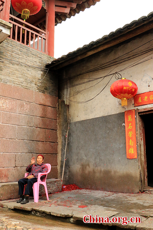 An old woman leans on a chair at the foot of the archway. Nowadays, more than 300 families still live here. [Photo by Li Huiru / China.org.cn]