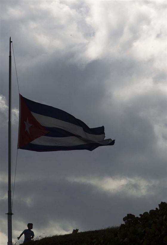 A boy stands below a Cuban national flag at half-mast in honor of Cuban revolutionary leader Fidel Castro, in Havana, capital of Cuba, on Nov. 27, 2016. [Photo/Xinhua]