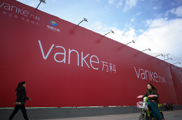 Pedestrians walk past an advertisement board of China Vanke Co Ltd. [China Daily]