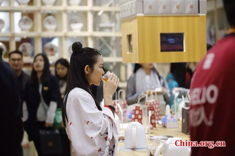 A young lady in a traditional Chinese garb drinks tea on Nov. 26, 2016. [Photo by Niu Jingjing / China.org.cn]