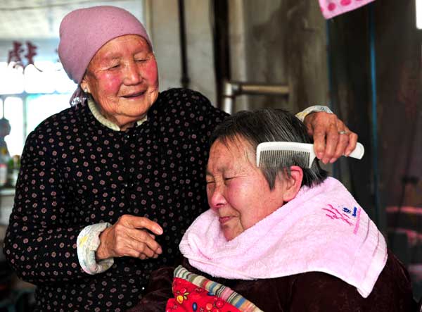 Sun Yincong combs the hair of her daughter-in-law Ren Caimei at their home in Yuncheng, Shanxi province. [For China Daily] 