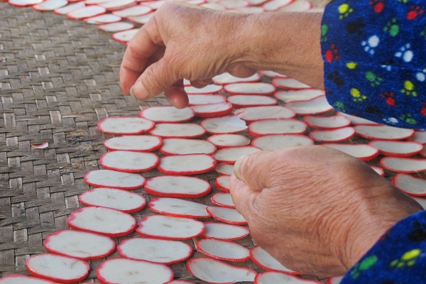 A lady carefully lays out sliced radish in a spiral. [Photo by Rosemary Bolger/chinadaily.com.cn]