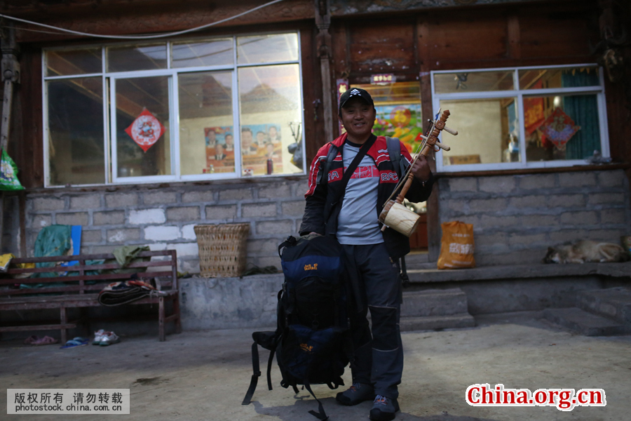 Aqingbu is packed and ready to set out for a long journey to clear garbage. His luggage includes a backpack, a sleeping bag and a 'Xuanzi' – a three-stringed musical instrument. [Photo by Bai Jikai/China.com.cn] 