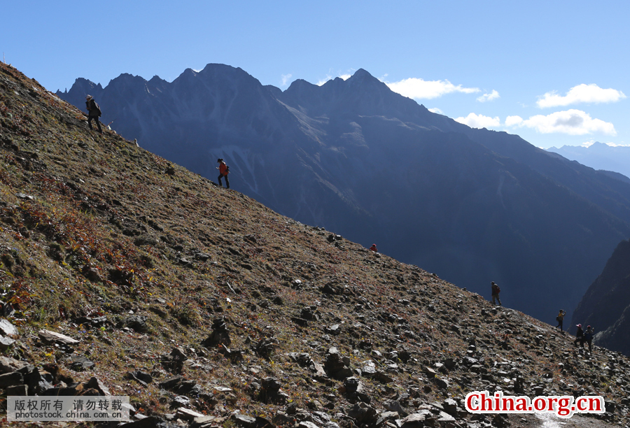 Villagers walk on a steep ridge at an altitude of more than 4,440 meters and clean up garbage along the way. [Photo by Bai Jikai/China.com.cn]