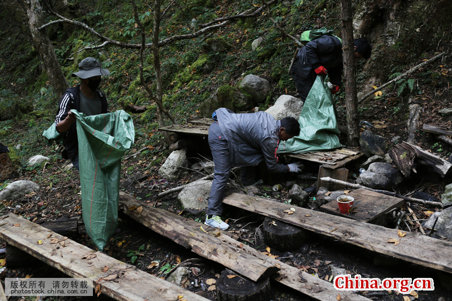 Villagers clean up garbage dropped by tourists at an abandoned tea booth on the mountain. [Photo by Bai Jikai/China.com.cn]