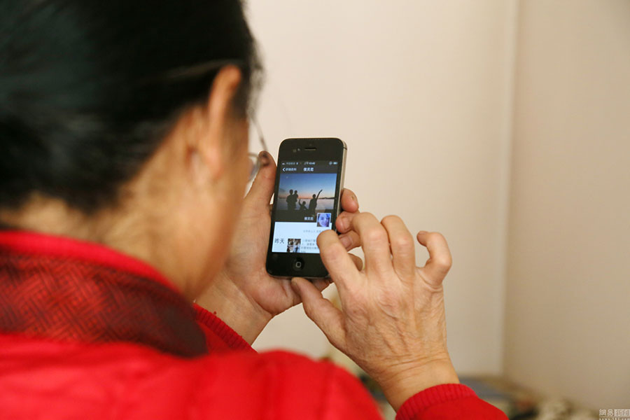 The 63-year-old woman looks through the pictures posted on her daughter's WeChat moments. [Photo: 163.com]