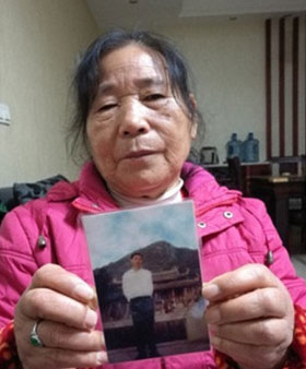 Bao Yuzhen holds a photo of her dead husband, the villager, Fan Anyin. [Photo: Baidu]