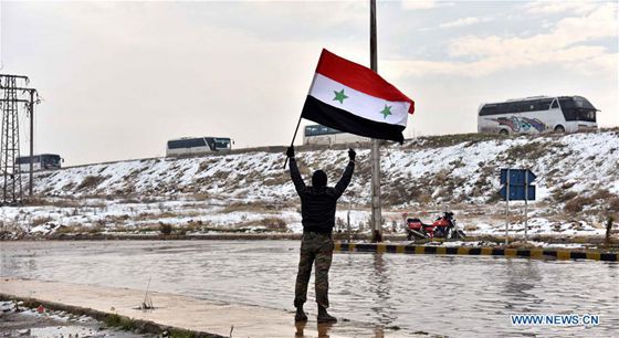 A man waves a Syrian national flag to the convoy with the opposition fighters onboard leaving Syria's northern city of Aleppo during an evacuation operation on Dec. 22, 2016. [Photo/Xinhua]