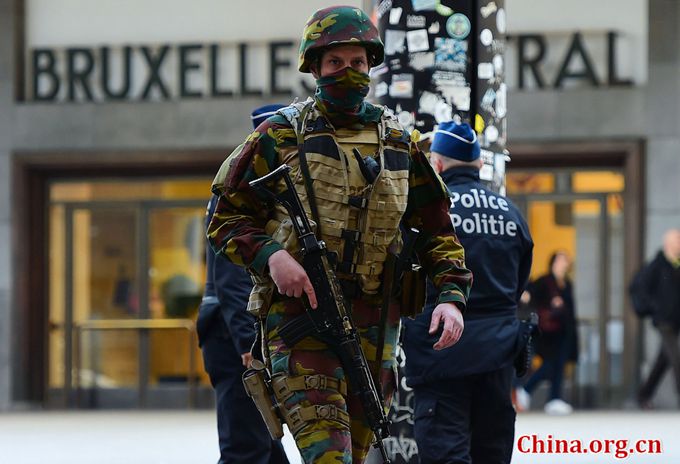 A Belgian soldier patrols outside Brussels Central Station as people are allowed in small group of ten to reach the station in order to take their commuter train following attacks in Brussels on March 22, 2016. [Photo/China.org.cn]