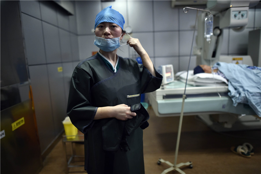 Liu Ya takes off surgical mask to catch a breath after operating an interventional radiology surgery. [Photo by Ran Wen/for China Daily]