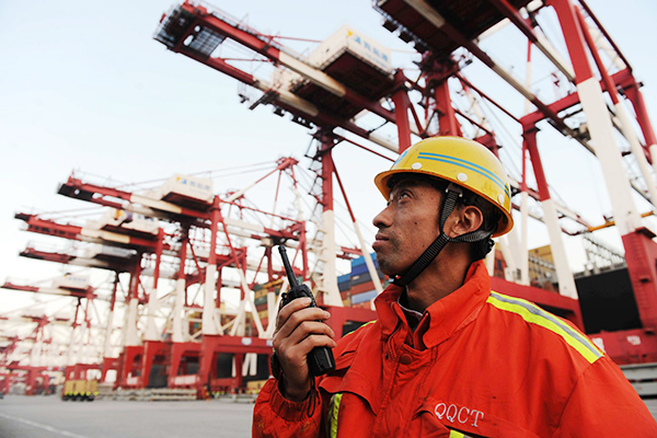 A worker looks closely as containers are unloaded in Qingdao Port, Shandong province. [Photo/China Daily] 