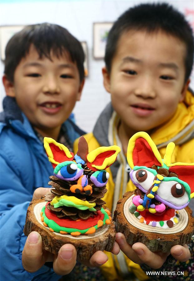 Two boys present clay artworks of &apos;nian&apos; made by themselves at a temple fair event for the upcoming Spring Festival in Tianjin, north China, Jan. 7, 2017. &apos;Nian&apos; ( Year in Chinese), is a mythical beast supposed to have preyed on people and livestock at the turn of the year. The monster, however, was afraid of loud bangs and red color. (Xinhua/Liu Dongyue)