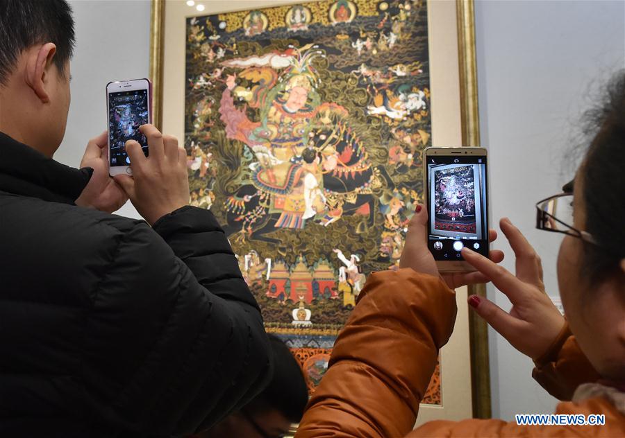 People take photos during an exhibition of Tibetan Thangka painting in Beijing, capital of China, Jan. 7, 2017. (Xinhua/Li He)