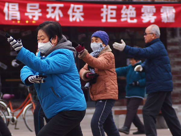 People exercise in Linfen, Shanxi province, on Tuesday morning. The slogan on the red banner reads,'Promote environmental protection and say 'No' to smog'.Xu Yin / For China Daily