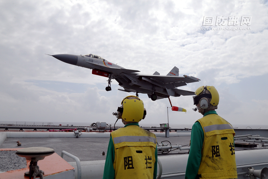 A J-15 carrier-based fighter jet, its tail hook down, tries to catch arresting wires to land on the Liaoning aircraft carrier during the vessel's latest training exercise. [Photo / MOD]