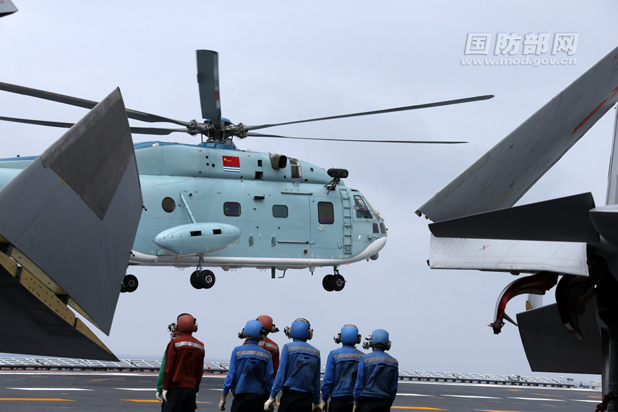 Crew work on the deck of the Liaoning aircraft carrier for the deck landing of a helicopter during the vessel's latest training exercise. [Photo / MOD]