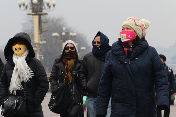 People wear masks at Tian'anmen Square in Beijing on Monday after the city issued a yellow alert for air pollution. [Photo/China Daily]