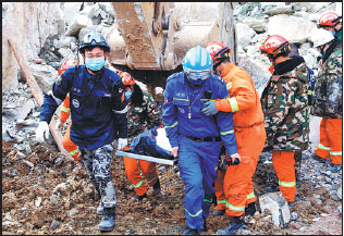 Rescuers retrieve a body from the rubble on Sunday after a landslide destroyed part of a hotel in Nanzhang county, Hubei province, on Friday. [Photo/Xinhua]
