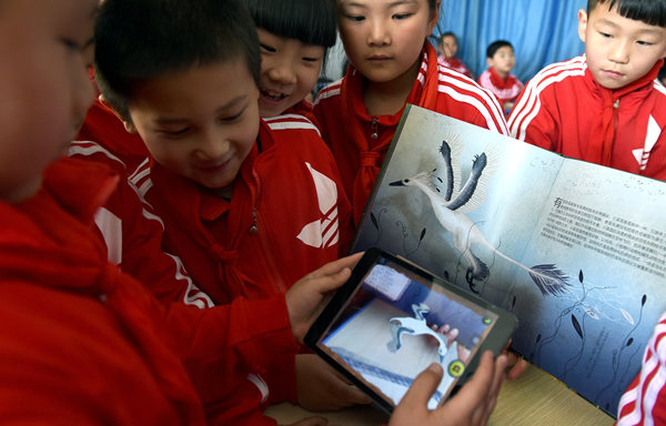 Students in a primary school in Hefei, capital of Anhui province, compare an e-book to a prited one in April. Young readers are expected to drive the growth of e-readers. [Photo/Xinhua]