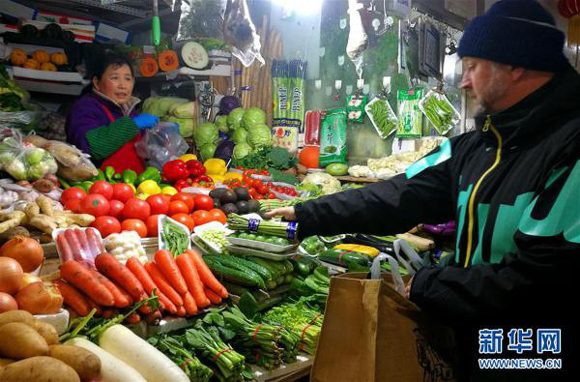 A foreigner buys vegetables in a food market in Beijing's Chaoyang District on Jan. 26, 2017. [Photo/Xinhua]