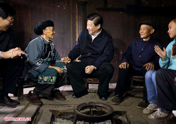 Chinese President Xi Jinping talks with family members of Shi Qiwen, a villager at Shibadong village in Paibi township of Huayuan county in the Tujia-Miao autonomous prefecture of Xiangxi, central China's Hunan province, Nov 3, 2013. [Photo/Xinhua]