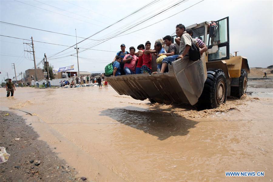 People cross a flooded road after the overflow of the Rimac river, in a sector of Huachipa, Lima, Peru, on March 16, 2017. The strong rains caused by the coastal El Nino phenomenon affected Lima since Wednesday afternoon. Flooding has claimed at least 62 lives as of Thursday and left countless people homeless, with 750 towns in 13 regions declared to be in a state of emergency. (Xinhua/Juan Carlos Guzman/ANDINA) 