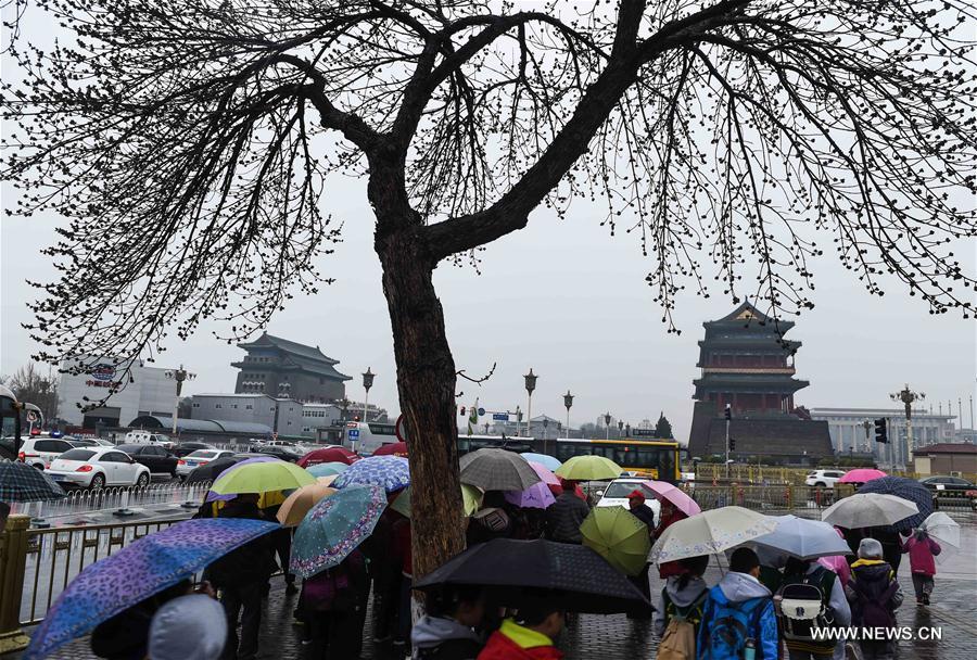 People walk in rain nearby the Tian&apos;anmen Square in Beijing, capital of China, March 23, 2017. A cold front brought rainfall to Beijing on Thursday, and a snowfall is expected to hit the city on Friday. (Xinhua/Luo Xiaoguang) 