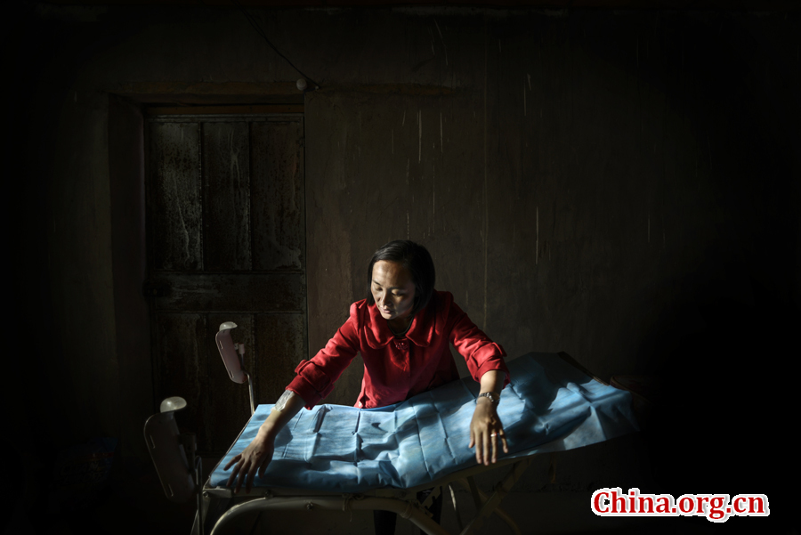 Doctor Ma Li carefully tidies up the medical bed in the clinic before the patients come. [Photo by Pan Songgang/China.org.cn] 